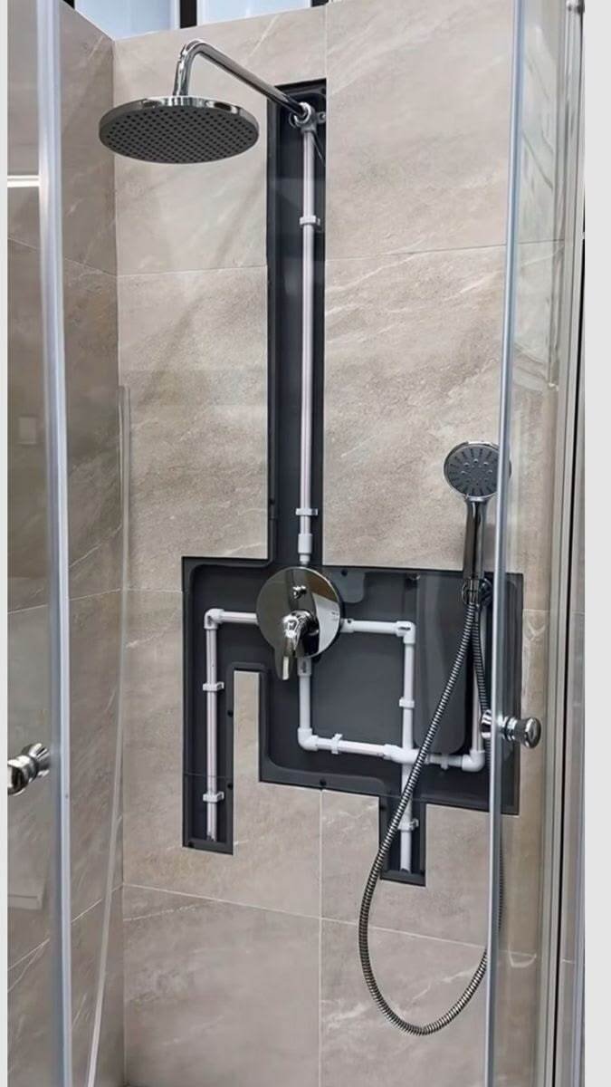 A tiled shower installation or repair with exposed in-wall plumbing.